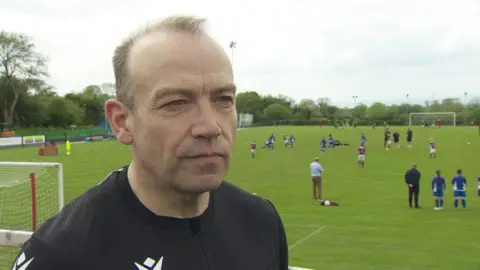 NI Secretary of State, Chris Heaton-Harris at a football pitch in south Antrim