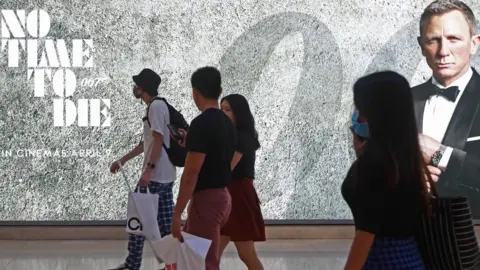 Suhaimi Abdullah/Getty Images People walk past poster for James Bond film No Time To Die in Singapore on 29 March