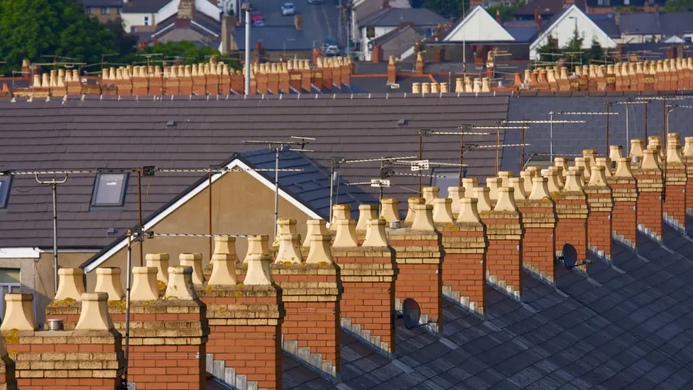 A picture of a row of house rooftops with chimneys