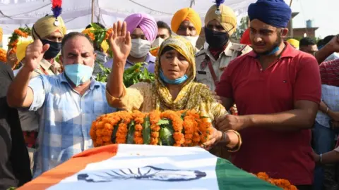 AFP Kashmir Kaur (C) gestures after laying the wreaths of flowers on the coffin of her son and soldier Satnam Singh