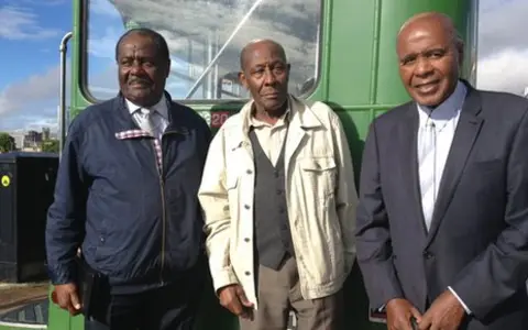 Guy Bailey, Roy Hackett and Paul Stephenson in front of one of the original green buses - modern photo