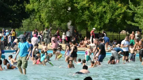 PA People in the paddling pool in Clissold Park, north London