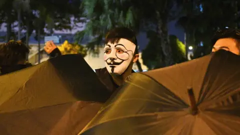 AFP A protester looks out from behind some umbrellas in Hong Kong