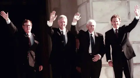 PA Media David Trimble, Bill Clinton, Seamus Mallon and Tony Blair wave on the steps of the Parliament Buildings at Stormont