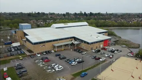 BBC Kettering Leisure Village - two story brick and glass leisure centre with car park
