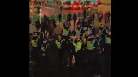 Snap More than a dozen police officers lead a man away from the scene of the fireworks incident