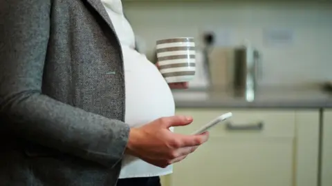  Mike Harrington via Getty Images Pregnant woman holding a phone