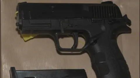 West Midlands Police A black handgun lying on its side. A cartridge is at the bottom of the picture.