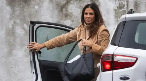 AFP via Getty Images Judge Julieta Makintach gets out of a white car outside a Buenos Aires court. She is wearing a beige coloured jumper and jacket.