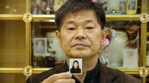 Mr Song holding a photo of his daughter Eun-ji