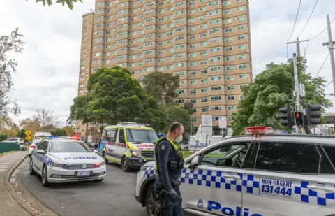 Getty Images Police cars and officers outside one of the locked-down towers in Melbourne