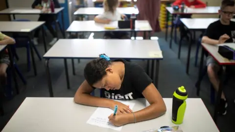 Reuters Girl sits at desk alone working after returning to socially distanced post-Covid-19 classroom