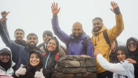 Haroon Mota A group of walkers on top of a peak