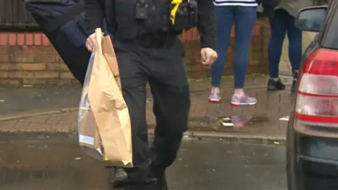 A police officer takes evidence away from the scene