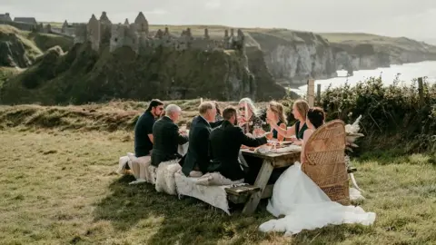 Epic Love Photography Jamie and Corey with guest enjoying a picnic overlooking Dunluce Castle
