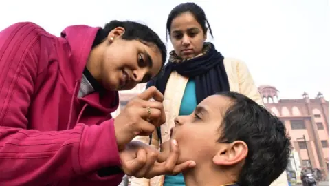 Getty Images Health workers administer polio drops to a child during the National Immunization Day, on January 19, 2020 in Amritsar, India.