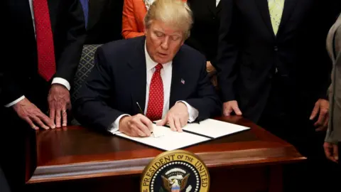 Getty Images President Donald Trump signs an Executive Order to begin the roll-back Obama-era environmental regulations on 28 February 2017