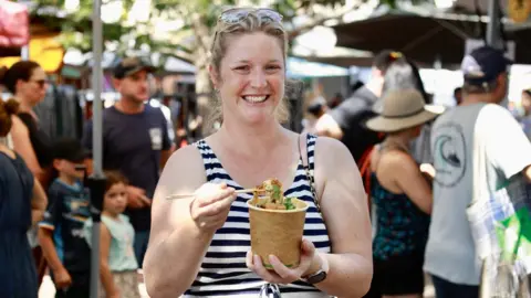 (A)manda Parkinson/BBC Kristy holding a cup of laksa