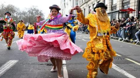 Reuters Performers dance down the street