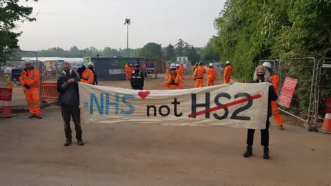 HS2 Rebellion Protestors holding a banner outside a HS2 site