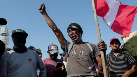 A man holding the flag of Peru with his fist in the air