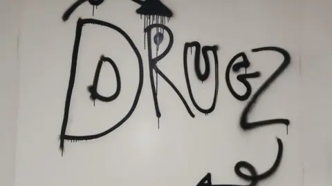 A white wall with black graffiti spelling out 'Drugz'