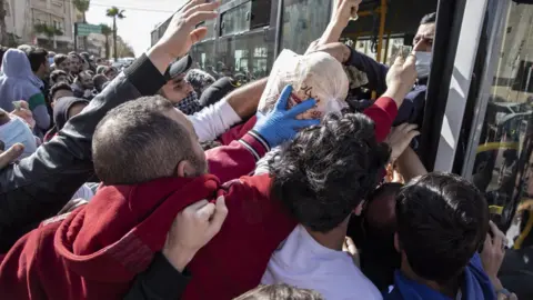 EPA People try to collect bread from municipal buses in Amman, Jordan (24 March 2020)