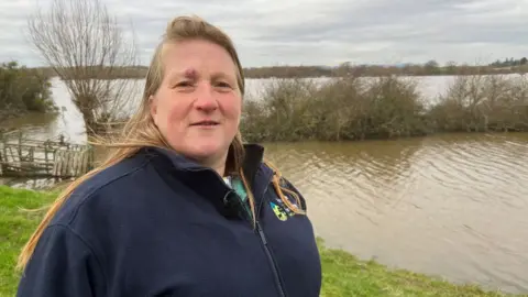 BBC Debbie Wilkins standing in front of a flooded field