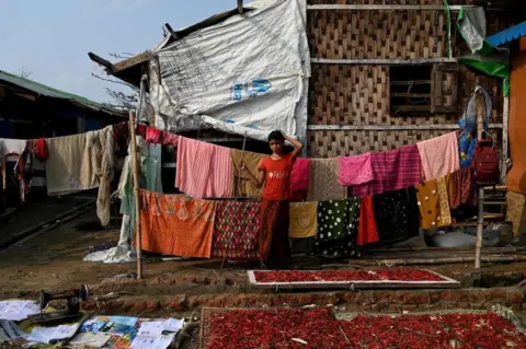 Getty Images A Rohingya girl stands next to her destroyed house at Ohn Taw Chay refugee camp in Sittwe on May 16, 2023, in the aftermath of Cyclone Mocha's landfall.