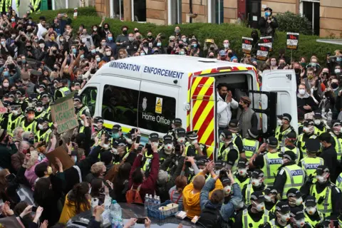 Andrew Milligan / PA Media A man is released from the back of an Immigration Enforcement van in Glasgow, accompanied by Mohammad Asif, director of the Afghan Human Rights Foundation.
