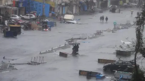 Getty Images People wade through floodwaters in Puri after Cyclone Fani hit