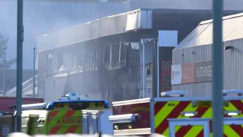 Wales News Service Burnt out gym building with emergency service vehicles in front