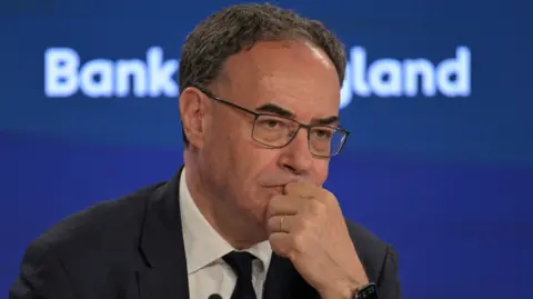 Reuters Governor of the Bank of England, Andrew Bailey during the Bank of England financial stability report press conference in July, 2026. He wears a dark jacket, white shirt and dark tie.
