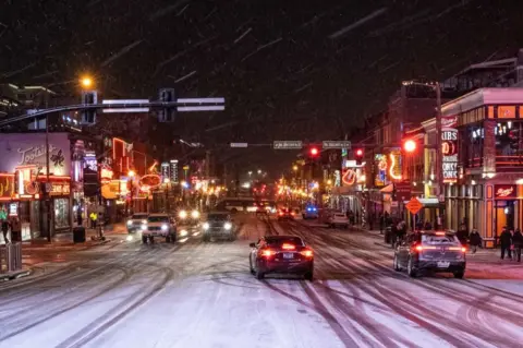 SETH HERALD/AFP Snow falls on Broadway, a popular tourist street in Nashville, Tennessee, on 22 December 2022