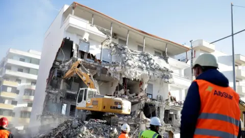 Reuters A bulldozer works at a collapsed building in Durres