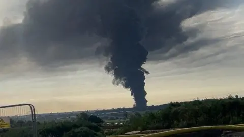 Davie Lloyd Huge black plumes of smoke billowing into the sky. This photo has been taken from a large distance away, demonstrating the scale of the fire.