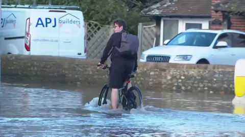 Person riding bike through flood water