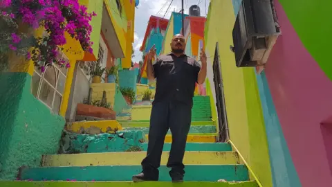 Duncan Tucker Enrique Gómez poses in a colourful alley in