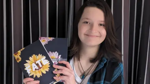 Alex Phillips-Hawkes Alex holds two books