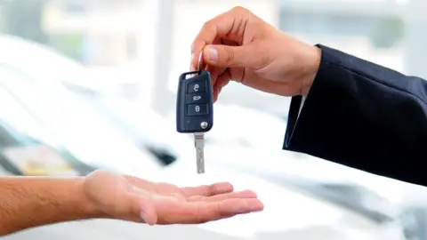 Getty Images Salesman hands over car key