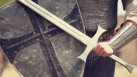 Getty Images Man holding sword and shield