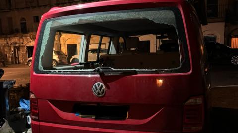 Image of a dark red Volkswagen van with a smashed 