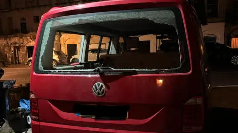 Family photo Image of a dark red Volkswagen van with a smashed 