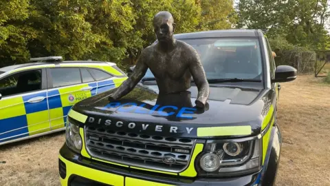 Alfie Best Top half of mannequin on top of police land rover bonnet