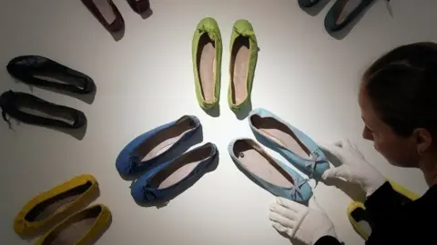 Reuters An employee poses as she adjusts a display of ballet pumps belonging to Audrey Hepburn