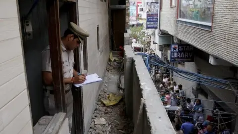 Reuters A policeman writes notes in the house where the bodies of eleven members of a family were found dead in Burari, in New Delhi, India, July 1, 2018