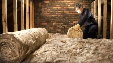 Getty Images Man laying loft insulation