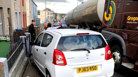 A car on the pavement following a collision with a truck on the A487