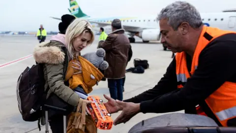 Reuters An Israeli man helps a Ukrainian refugee as she arrives on a flight from Romania at Tel Aviv's Ben Gurion airport (8 March 2022)