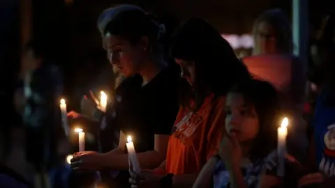 Getty Images People hold candles during a vigil for the stabbing attack victims in Saskatchewan.